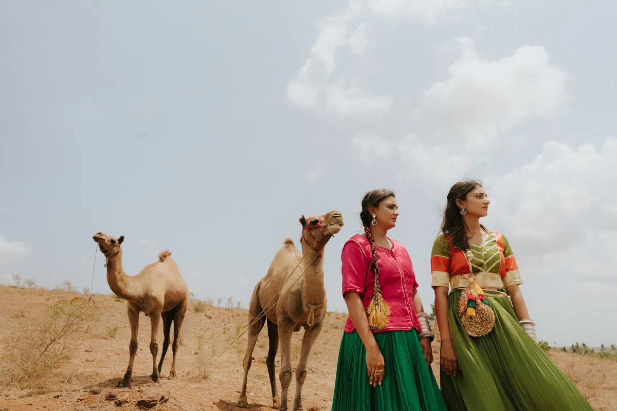 Fashion portrait of two women in pink and green outfits with camels