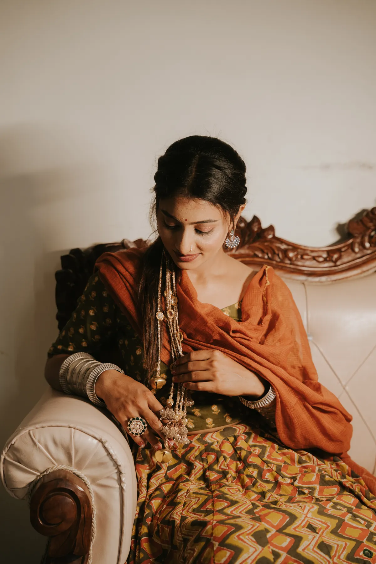 Seated portrait with an orange dupatta and silver jewellery